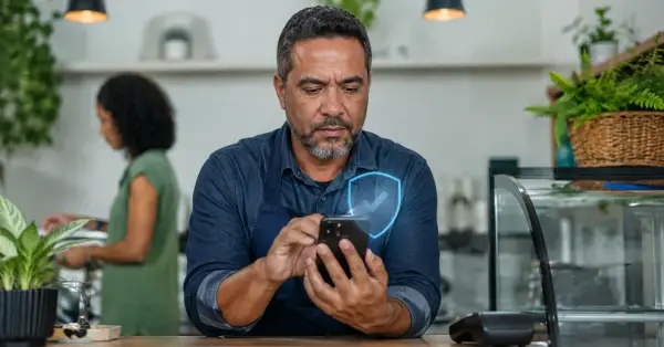 Comerciante confere pagamento no celular com símbolo de segurança