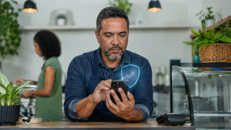 Comerciante confere pagamento no celular com símbolo de segurança